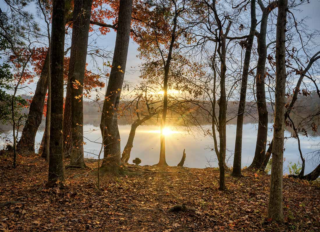Garner, NC - Scenic View of the Sun Settings Over a Lake in the Woods During the Fall in Garner North Carolina